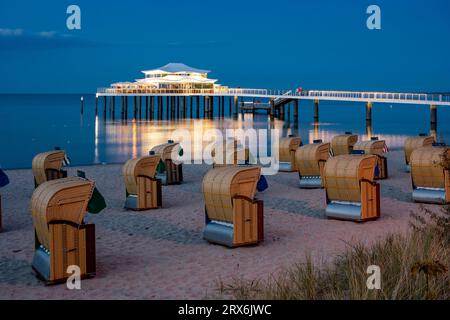 Deutschland, Schleswig-Holstein, Timmendorfer Strand, Strandliegen mit Kapuze mit Pier und Mikado Teehaus im Hintergrund Stockfoto