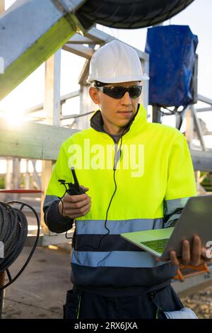 Ingenieur mit Laptop und Walkie-Talkie durch die Wartungsmaschine der Windkraftanlage Stockfoto