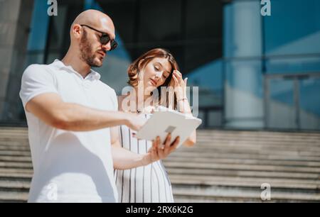 Junge Führungskräfte diskutieren über Statistiken, Kosten, Projekte und Rentabilität. In lässiger Kleidung arbeiten sie im Freien in einem Stadtviertel zusammen und zeigen Erfolg Stockfoto