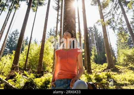 Frau mit geschlossenen Augen im Wald an sonnigen Tagen Stockfoto