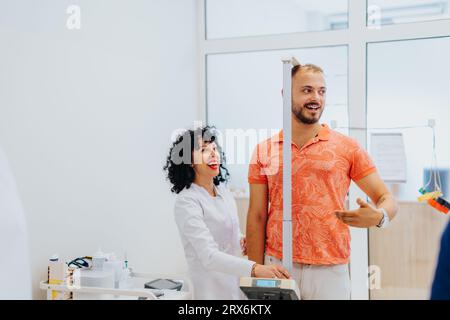 Ärzte und Spezialisten führen ärztliche Untersuchungen durch, messen die Höhe in einem Krankenhauszimmer. Die Patienten erhalten umfassende medizinische Unterstützung von prof. Stockfoto