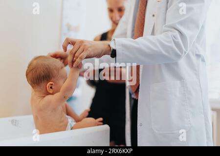 Kinderarzt mit niedlichem Baby in der Klinik. Kinderärztin, die Babyhände hält. Stockfoto