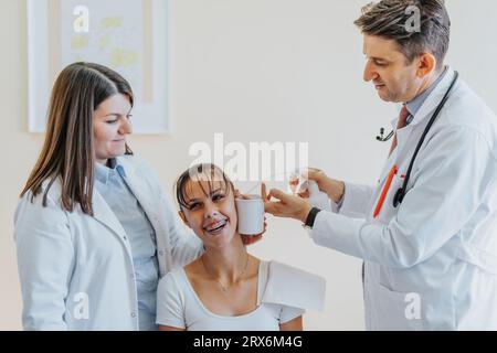 Eine professionelle Ärztin untersucht einen jungen Patienten in einer Klinik und überprüft dabei Sehvermögen, Gehör und Hals. Stockfoto