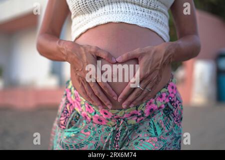 Schwangere Frau macht Herzform mit Hände auf Bauch Stockfoto