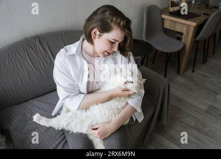 Junge Frau streichelte Katze auf dem Sofa Stockfoto