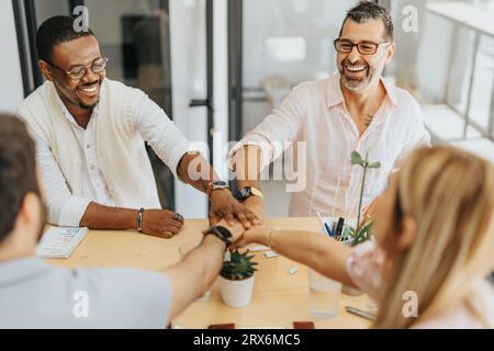 Hände zusammenlegen. Erfolgreiches Geschäftsteam, das nach der Annahme eines neuen Geschäftsabschlusses bei der Arbeit die Hände zusammenbringt. Stockfoto