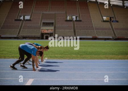 Junge Leute in einer Unisex-Sportbekleidung warten auf ein Schild, um auf 100 Metern zu sprinten Stockfoto