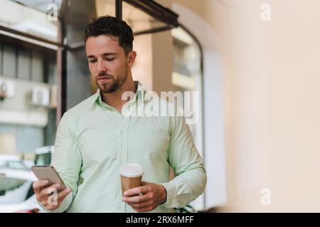 Junger Geschäftsmann, der im Café ein Smartphone benutzt Stockfoto
