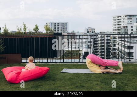 Vater macht Yoga und Tochter sitzt auf dem Dach Stockfoto
