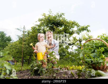 Glückliche Mutter und Tochter mit Gießkanne im Garten Stockfoto