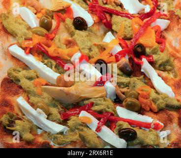 Gourmet-Pizza mit Basilikum-Pesto-Tomate und Mozzarella und Oliven zum Verkauf in der Pizzeria Stockfoto