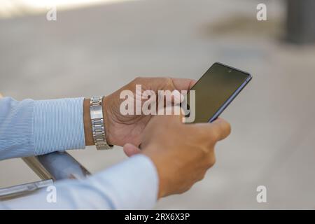 Detail der Hände eines hispanischen Mannes mit einem Mobiltelefon. Stockfoto