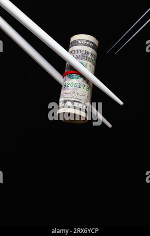 Chinesische Rache. Holzstäbchen haben eine amerikanische Dollarrechnung Stockfoto