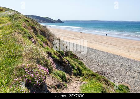 Menschen, die am Newgale Beach im Pembrokeshire Coast National Park, West Wales, Großbritannien, spazieren gehen Stockfoto