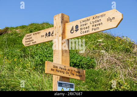 Schild für den Wales Coast Path (Drachenschale) und Pembrokeshire Coast Path (Eichel) am Nolton Haven Beach, Pembrokeshire Coast National Park, Wales UK Stockfoto