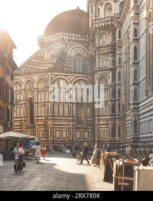 Florenz, Italien - 15. Juli 2023: Detail der Kathedrale Santa Maria del Fiore in der Dämmerung Menschen gehen auf der Straße Künstlerstationen bereit für einen neuen Tag W Stockfoto