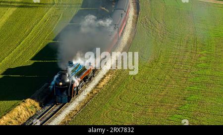 Ein Luftblick auf einen stromlinienförmigen Dampfzug, der an einem Herbsttag um eine Kurve fährt und Rauch bläst Stockfoto