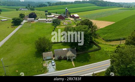 Ein Luftblick am späten Nachmittag auf Ackerland, Maisfelder, abgeerntete Felder, Silos, Barns und Rural Road, Sommertag Stockfoto