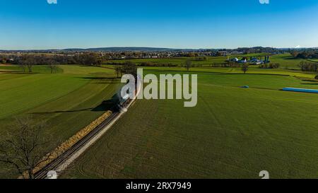 Ein Luftblick auf einen stromlinienförmigen Dampfzug, der an einem Herbsttag um eine Kurve fährt und Rauch bläst Stockfoto