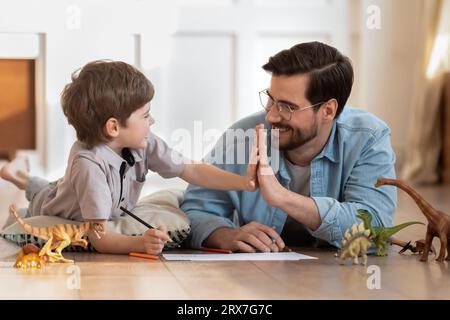 Glücklicher Vater und Sohn, die High Five geben und auf dem Boden spielen Stockfoto