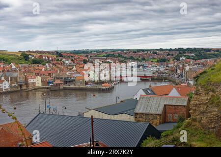 Whitby, England, 9. August 2023. Blick von West Cliff über die Gebäude mit der Drehbrücke und dem Hafen im Hintergrund Stockfoto