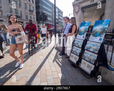 Jehovahs Zeugenstand im Oxford Circus, London, Großbritannien, mit Käufern, die an H&M Hennes und Mauritz Store vorbeigehen Stockfoto