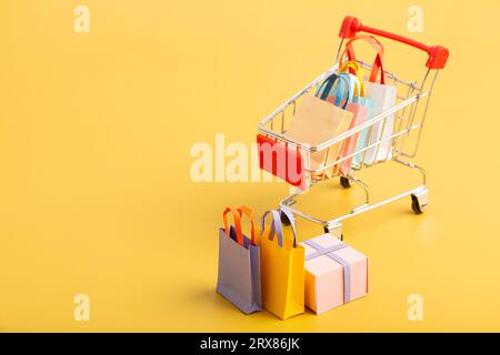 Trolley-Wagen mit bunten Papiertüten isoliert. Kreative Idee für Online-Shopping, Verkauf, Supermarkt, Rabattaktion und Sommerverkauf Konz Stockfoto