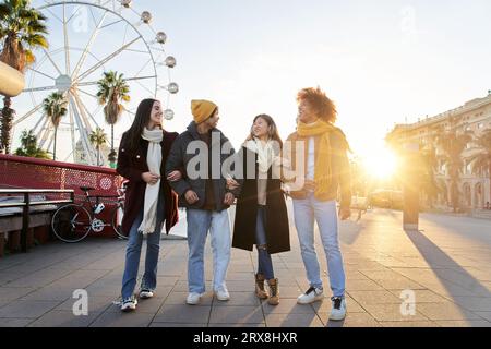 Gruppe von Freunden, die bei Tageslicht durch den Vergnügungspark spazieren. Freunde treffen sich zusammen Stockfoto
