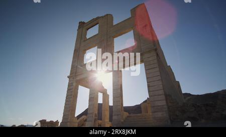 Die Umgebung Desert Sun blickt durch ein oberes Fenster der berühmten Cook Bank Ruinen in Rhyolite, Nevada. Stockfoto