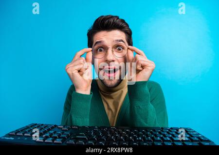 Nahaufnahme eines aufgeregten jungen Programmierers in der Nähe von mechanischer Tastatur und digitaler Technologie Geek überrascht isoliert auf blauem Hintergrund Stockfoto