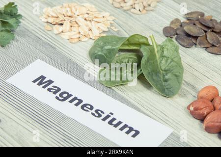Inschrift Magnesium, gesunde nahrhafte Lebensmittel und verschiedene Zutaten, die natürliches Magnesium und andere Vitamine und Mineralien enthalten Stockfoto