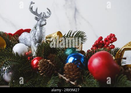 Dekorative Weihnachtskomposition aus Tannenzweigen für Tisch oder Kamin. Rentierspielzeug und goldene Bänder mit Bobbles und Beeren. Nahaufnahme Stockfoto