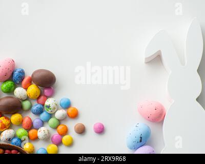 Süßes Osterkonzept. Farbenfrohe ostereier mit Schokolade und süßem Dragee auf weißem Hintergrund mit Kopierbereich. Entwurf einer Grußkarte für den EAS Stockfoto