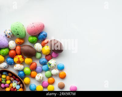 Süßes Osterkonzept. Farbenfrohe ostereier mit Schokolade und süßem Dragee auf weißem Hintergrund mit Kopierbereich. Entwurf einer Grußkarte für den EAS Stockfoto