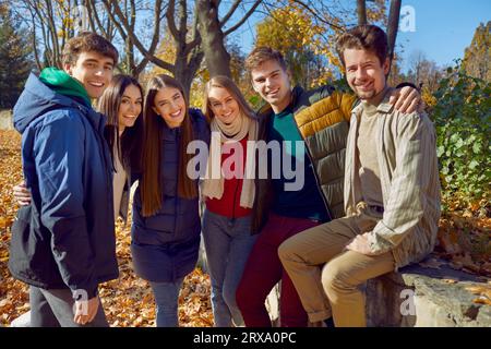 Glückliche männliche und weibliche Freunde umarmen sich im Herbstpark. Stockfoto