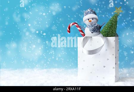 Weihnachts-Schneemann mit Einkaufstasche auf Schnee und Weihnachtsgeschenk. Banner für Winterangebote. Liefergeschenke. Schneemann verschenken Stockfoto