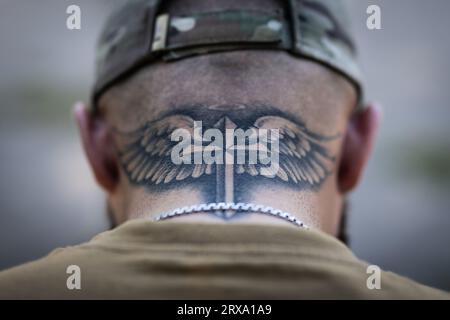 Kostjantyniwka, Ukraine. September 2023. Roman (24), ein gläubiger ukrainischer Soldat, der an der Front mit der 3. Sturmbrigade kämpft, hat ein schwertförmiges Kreuz, das von Engelsflügeln auf seinem Nacken tätowiert ist. Er bekam das Tattoo zu Beginn des Krieges als Schutz. Quelle: Oliver Weiken/dpa/Alamy Live News Stockfoto