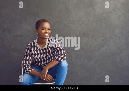 Porträt einer glücklichen und selbstbewussten dunkelhäutigen lässigen Frau, die beim Blick auf die Kamera lächelt. Stockfoto