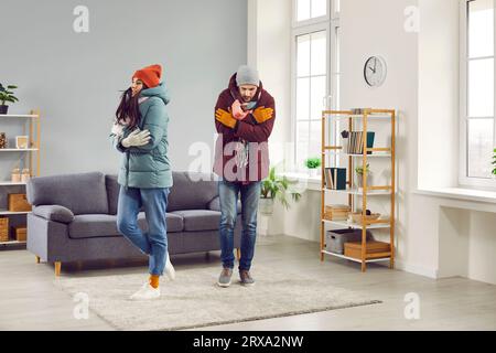 Traurige zitternde Menschen in Winterjacken, die in einer kalten Wohnung frieren Stockfoto