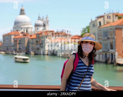 Schöne junge Touristin mit Maske und Strohhut, die Venedig während der Abriegelung in Italien besucht Stockfoto