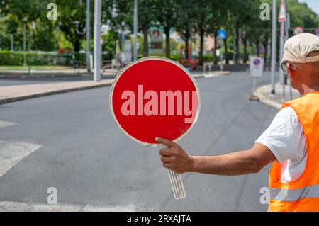 Bauarbeiter, der ein rotes Stoppschild hält und den Verkehr auf die Straße lenkt Stockfoto