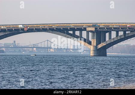 Bogen der U-Bahn-Brücke (Brovary Avenue) über den Dnieper in Kiew, Ukraine. Im Hintergrund der Pishokhidnyy Nebel Cherez Dnipro (Fußgänger Stockfoto