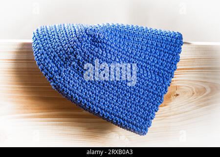 Strickmütze aus großem blauem Garn auf einem Hintergrund aus natürlichem Holzständer Stockfoto