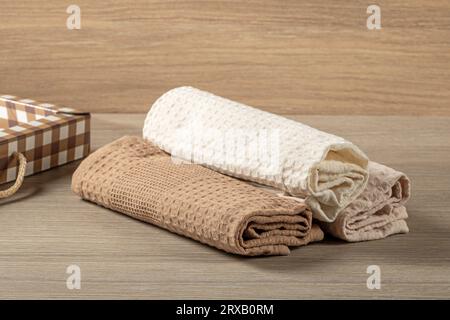 Waffelhandtücher, die in eine Rolle gerollt werden, werden auf einem Holztisch gestapelt, von oben gesehen, Hausleben Stockfoto
