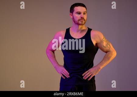 Passen Sie den jungen muskulös bärtigen Athleten in stilvoller Sportkleidung mit Armen auf den Hüften Porträt in voller Körperlänge isoliert über weißem Studiohintergrund. Stockfoto