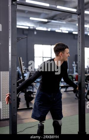 Junger, toller Mann, der Spaß im Fitnessstudio hat. Lächelnder Mann wird durch Workout, Glück und Lebensfreude genüsslich Stockfoto