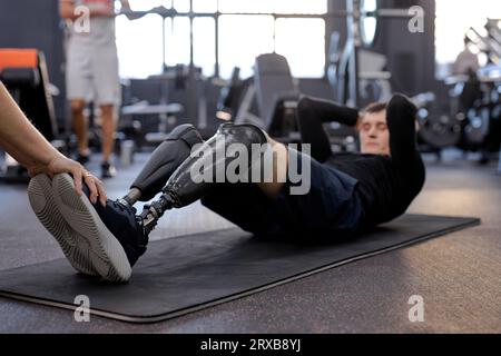 Die Liebe zum Leben. Freizeit, Freizeit, Lifestyle. Motivation, Seitenansicht, durchgehende Aufnahme, fit bleiben. Fleißiger aktiver Mann, der auf dem Boden liegt und sich hallo beugt Stockfoto