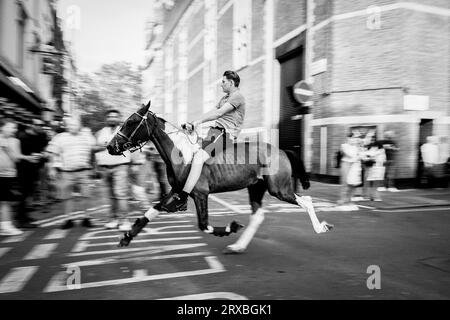 London Schwarzweiß-Straßenfotografie: Ein Jugendlicher reitet auf einem Pferd auf der griechischen Straße in Soho, London, Großbritannien. Stockfoto