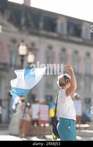 Eine Frau, die bei der Kundgebung die Flagge des Freien Russlands hält. Vertikale Aufnahme Stockfoto