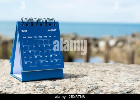 Blauer August-Kalender 2024 auf verschwommenem Hintergrund des blauen Ozeans. Neujahrskonzept 2024 Stockfoto